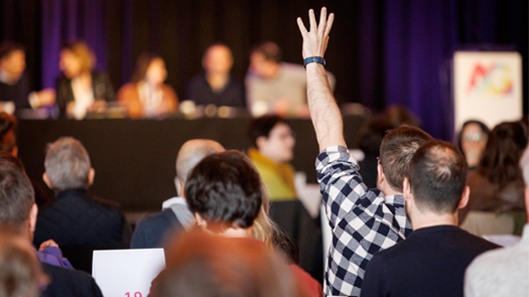 Homme de dos levant la main dans une assemblée